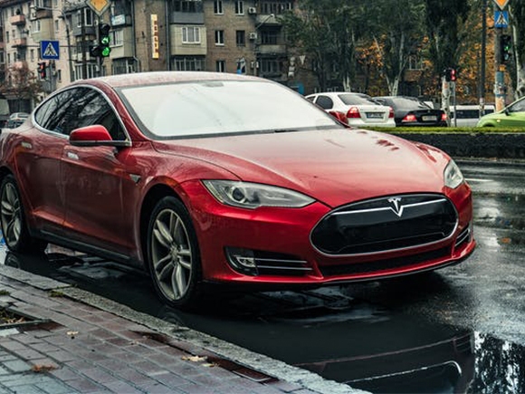A red tesla car on the roadside