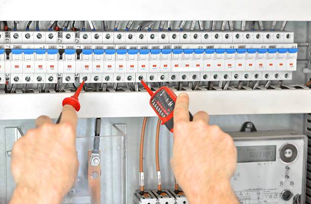 Hands of technician examining fusebox with multimeter probe